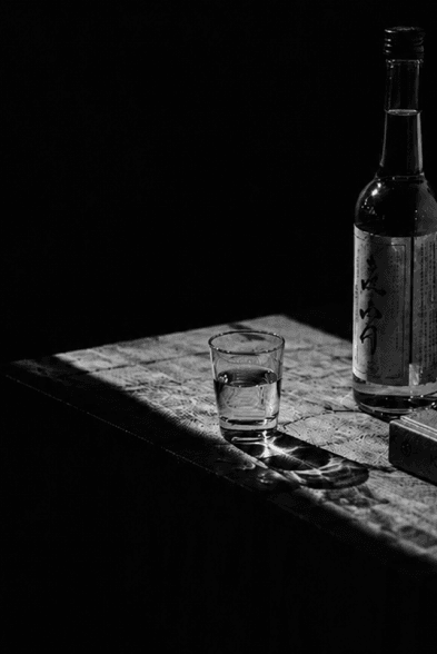 A bottle and glass of Korean alcohol on a dark wooden table